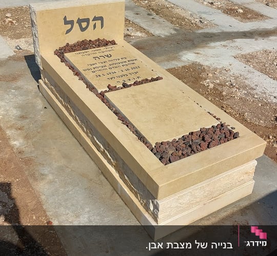 מצבה עם כיתוב בעברית ואבנים קטנות